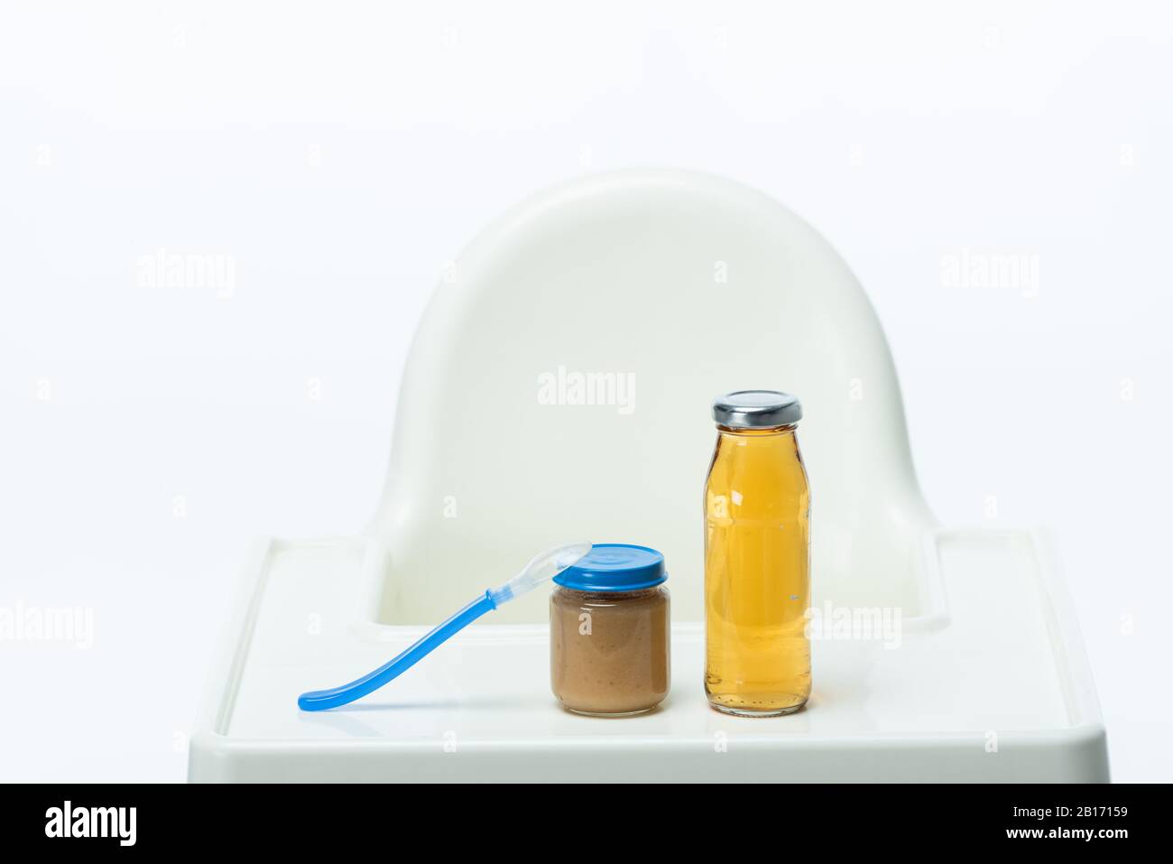 Jar of baby food with spoon and bottle of apple juice on table of