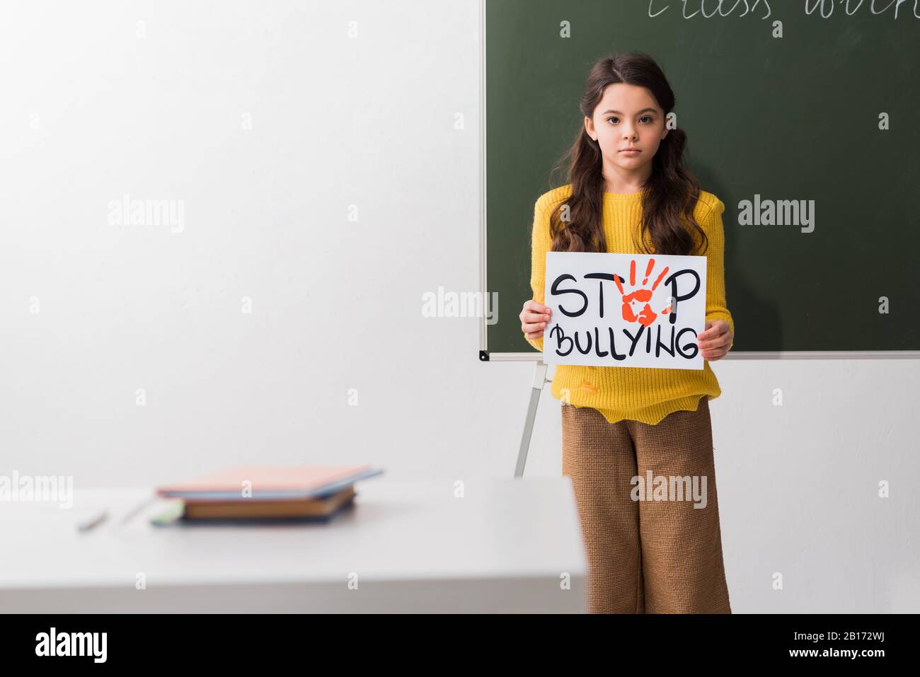 selective focus of schoolgirl holding placard with stop bullying ...