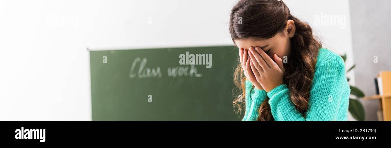 upset and bullied schoolgirl crying in classroom Stock Photo