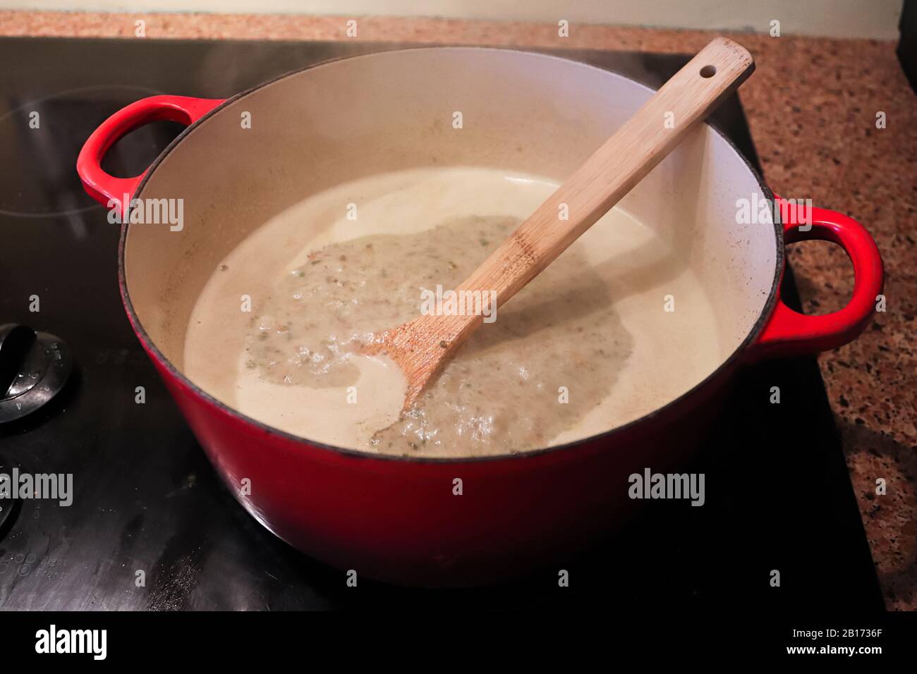A pot of cream based broth cooking on the stove Stock Photo Alamy