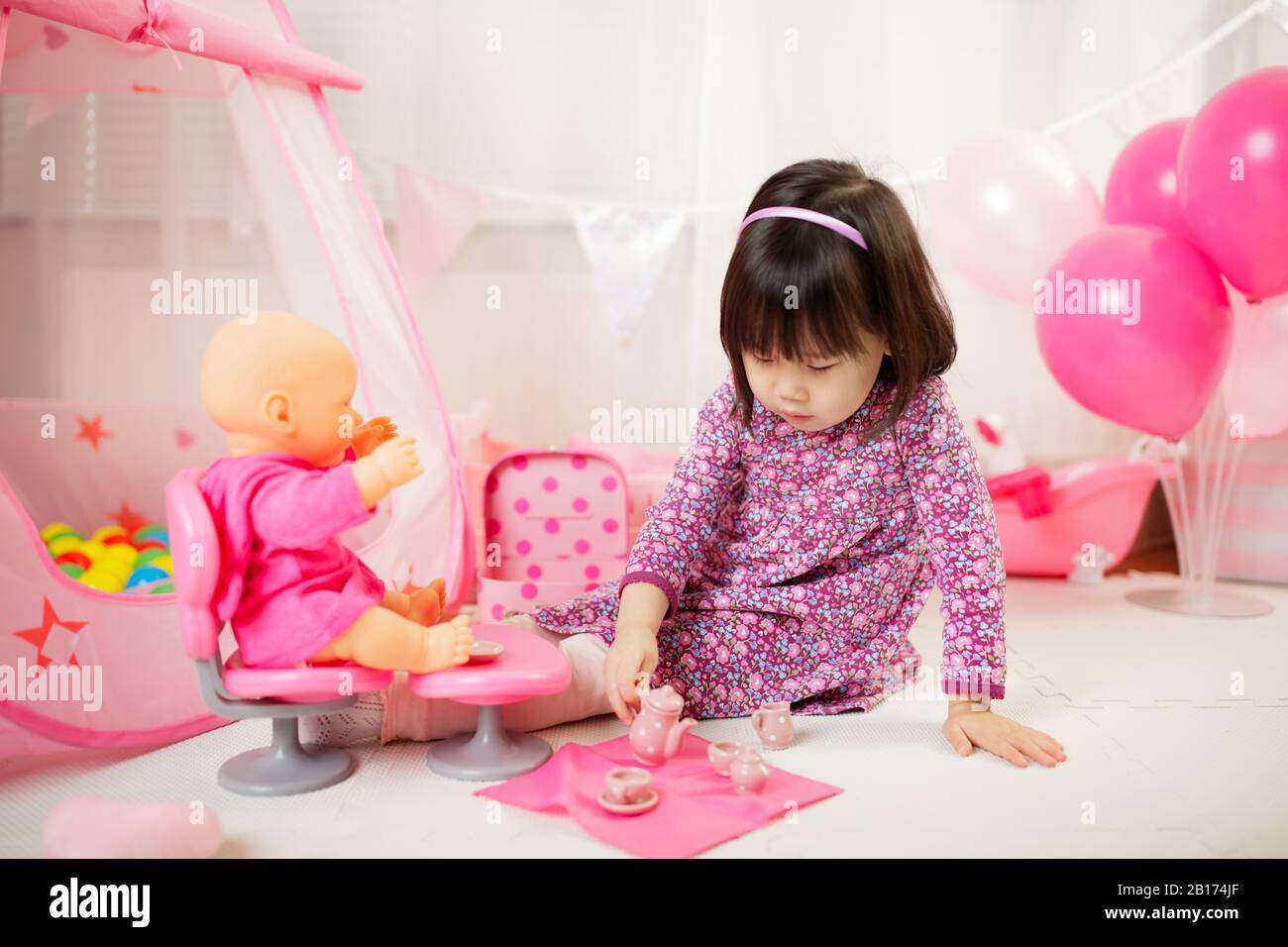 toddler girl pretend play baby care at home against white background