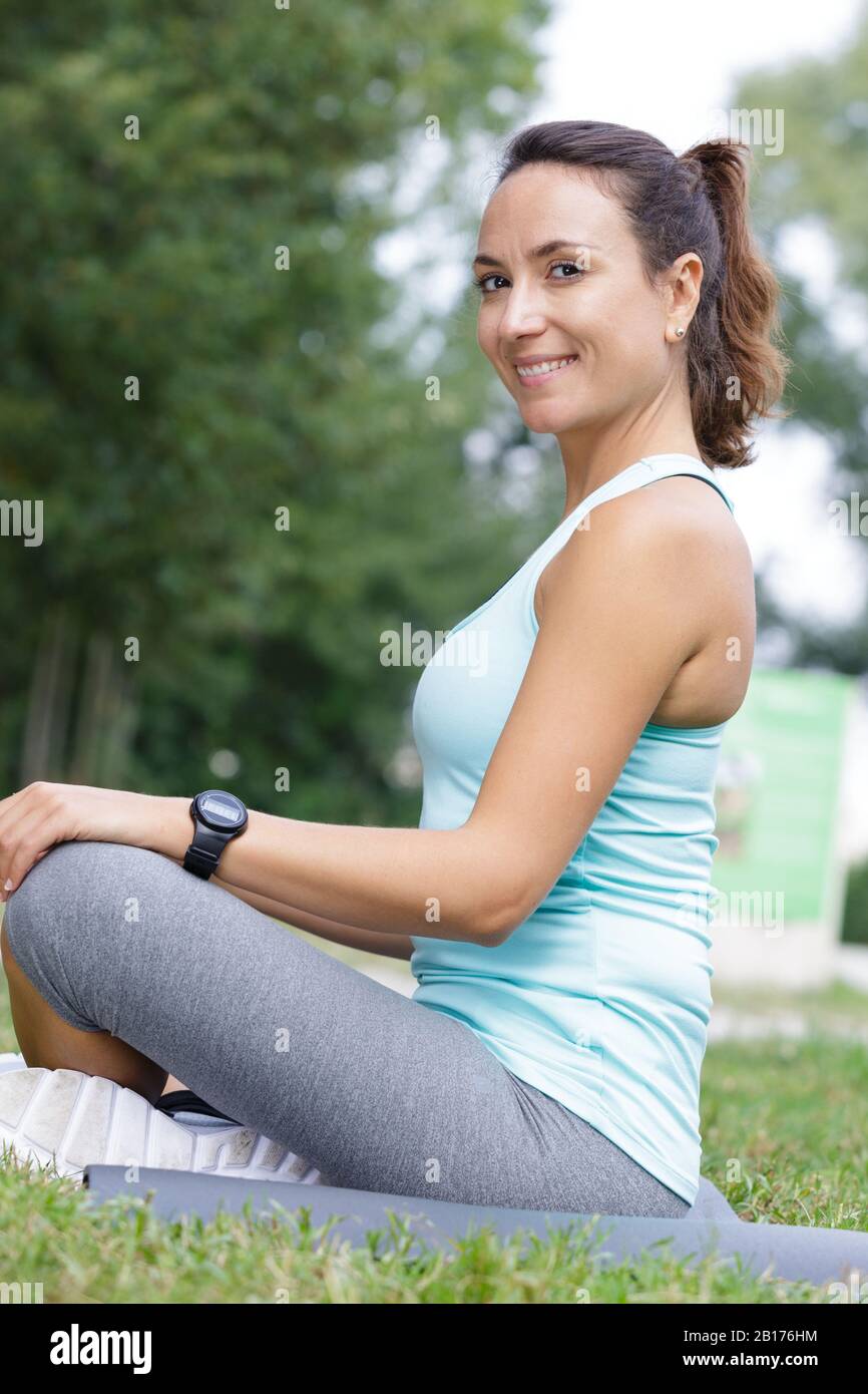 sporty lady sitting in lotus pose for meditation on grass Stock Photo