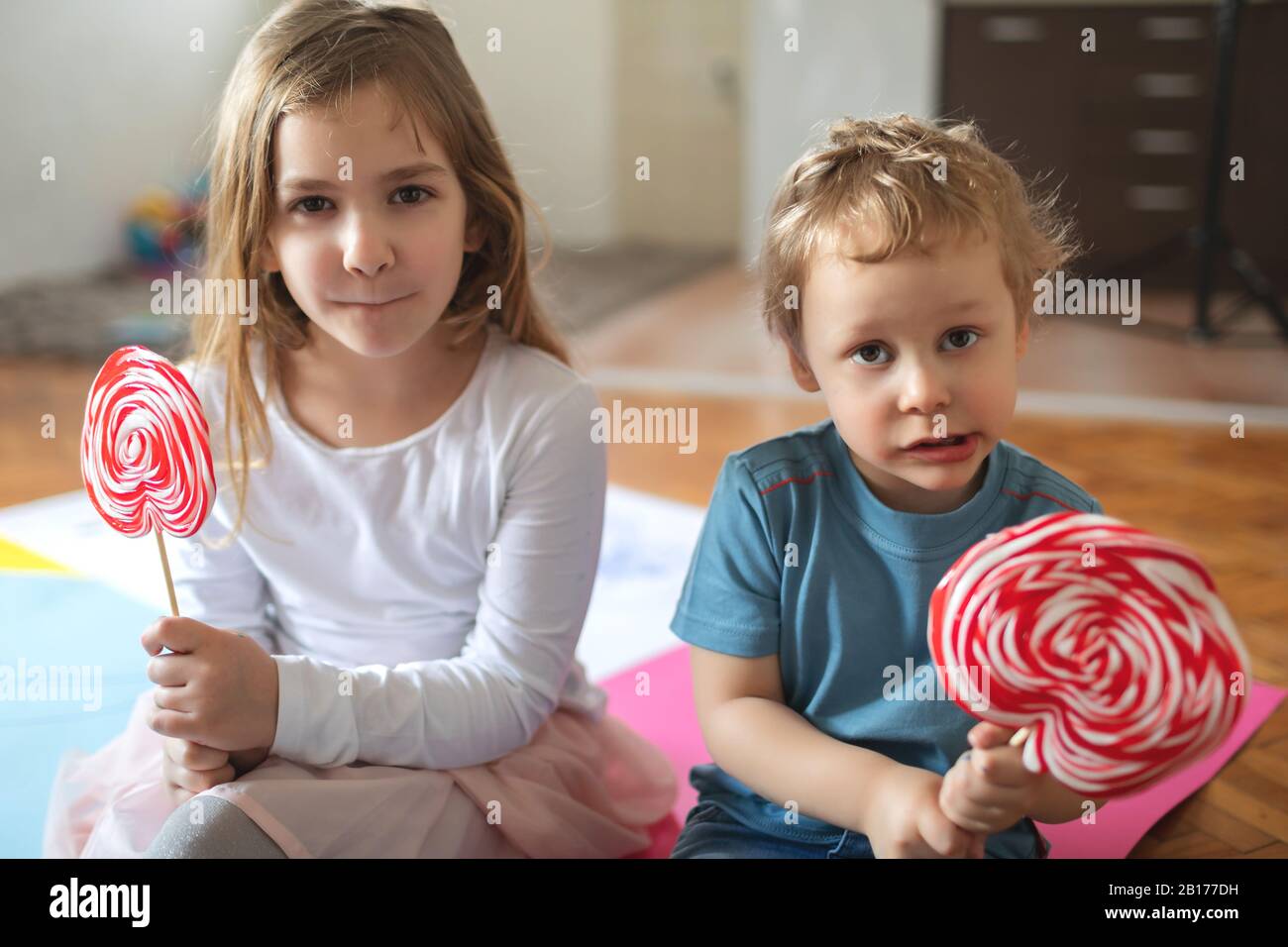Two kids play and eat lollypops Stock Photo