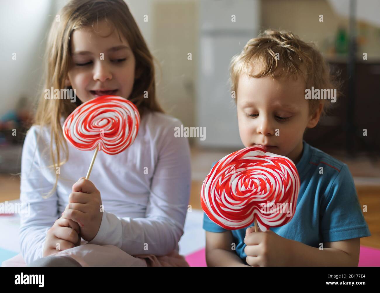 Two kids play and eat lollypops Stock Photo