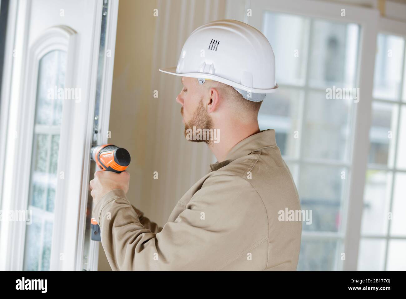 workman using cordless drill on pvc door Stock Photo