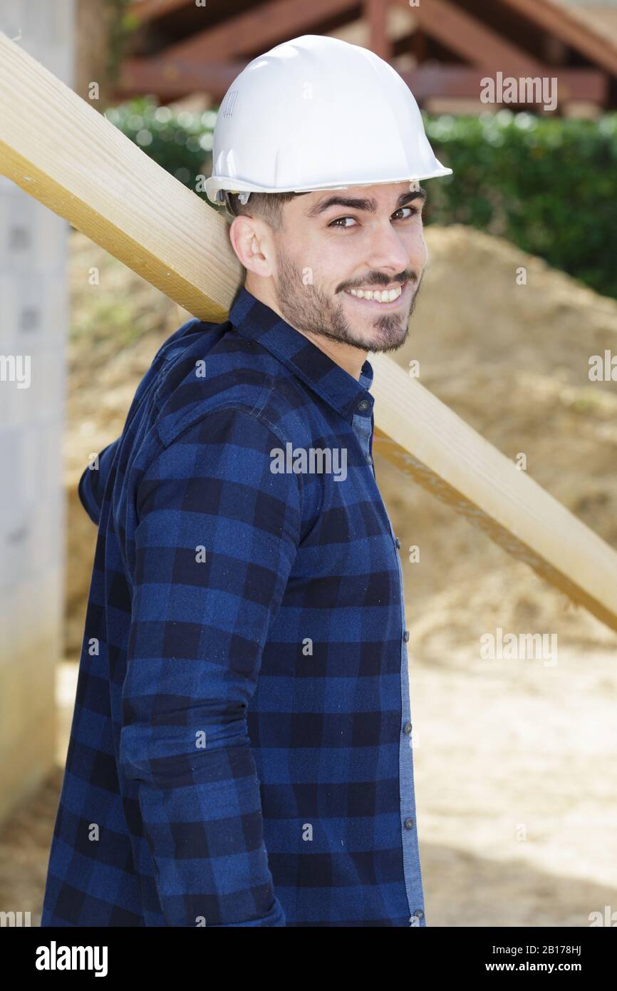 labourer carrying length of wood on his shoulder Stock Photo