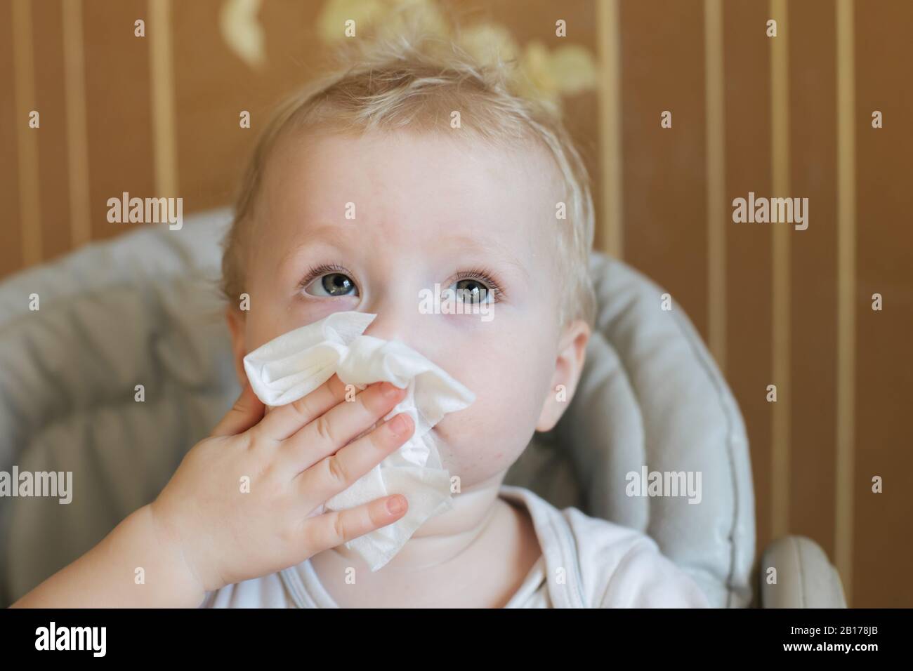 child wipes his nose with white handkerchief. Coronavirus symptom Stock Photo
