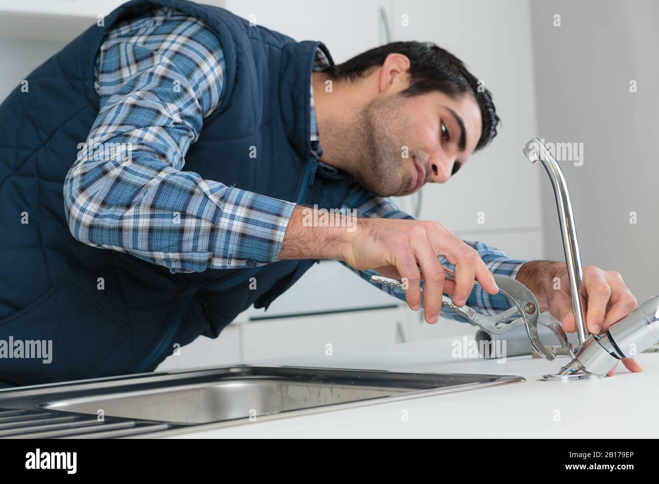 a plumber removing kitchen faucet Stock Photo