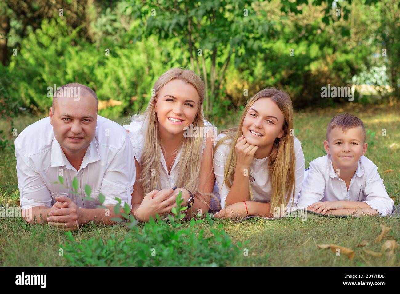 happy family laying on grass in the park isolated green grass foliage ...