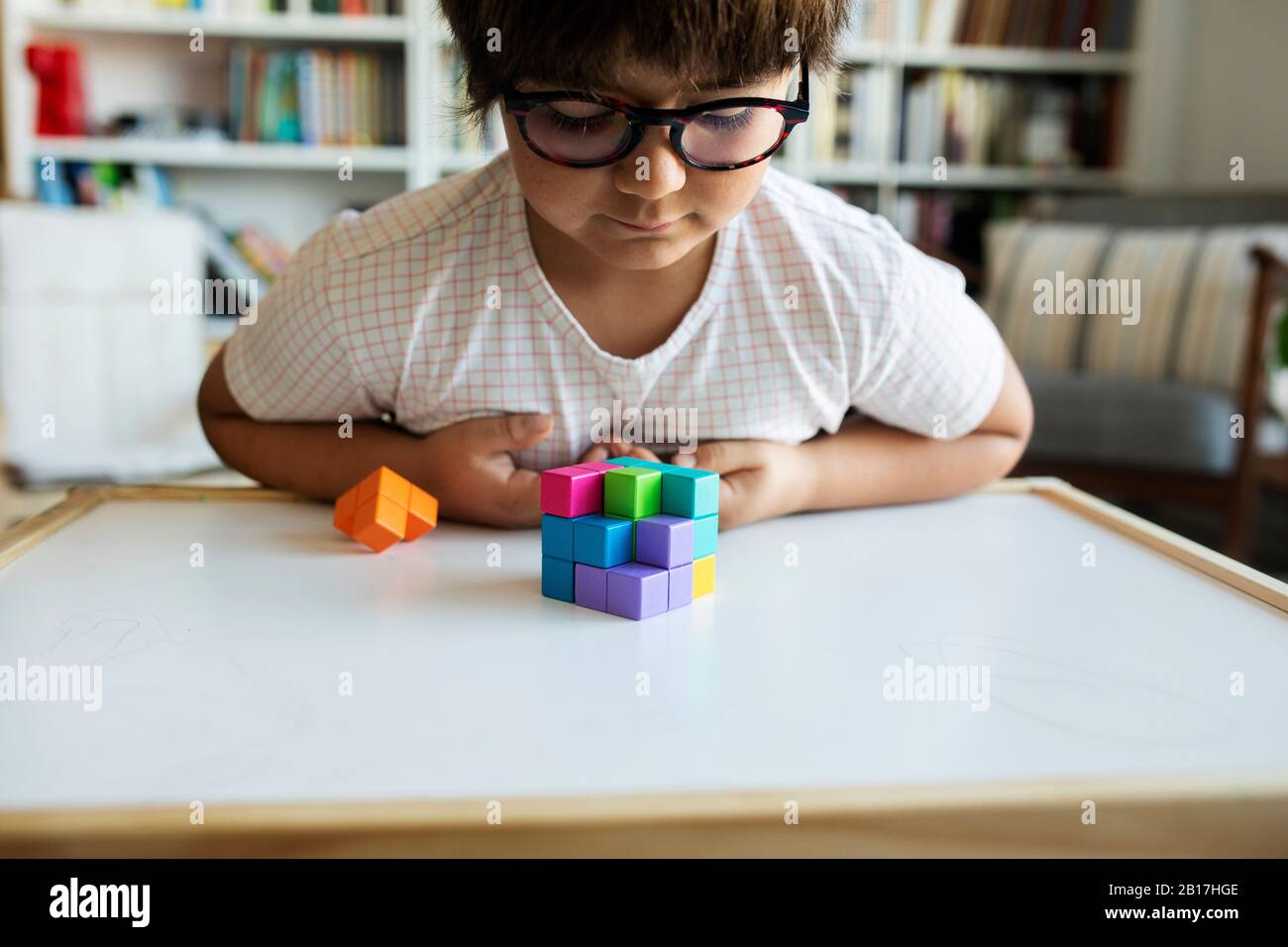 Little boy with glasses playing with building blocks at home Stock Photo