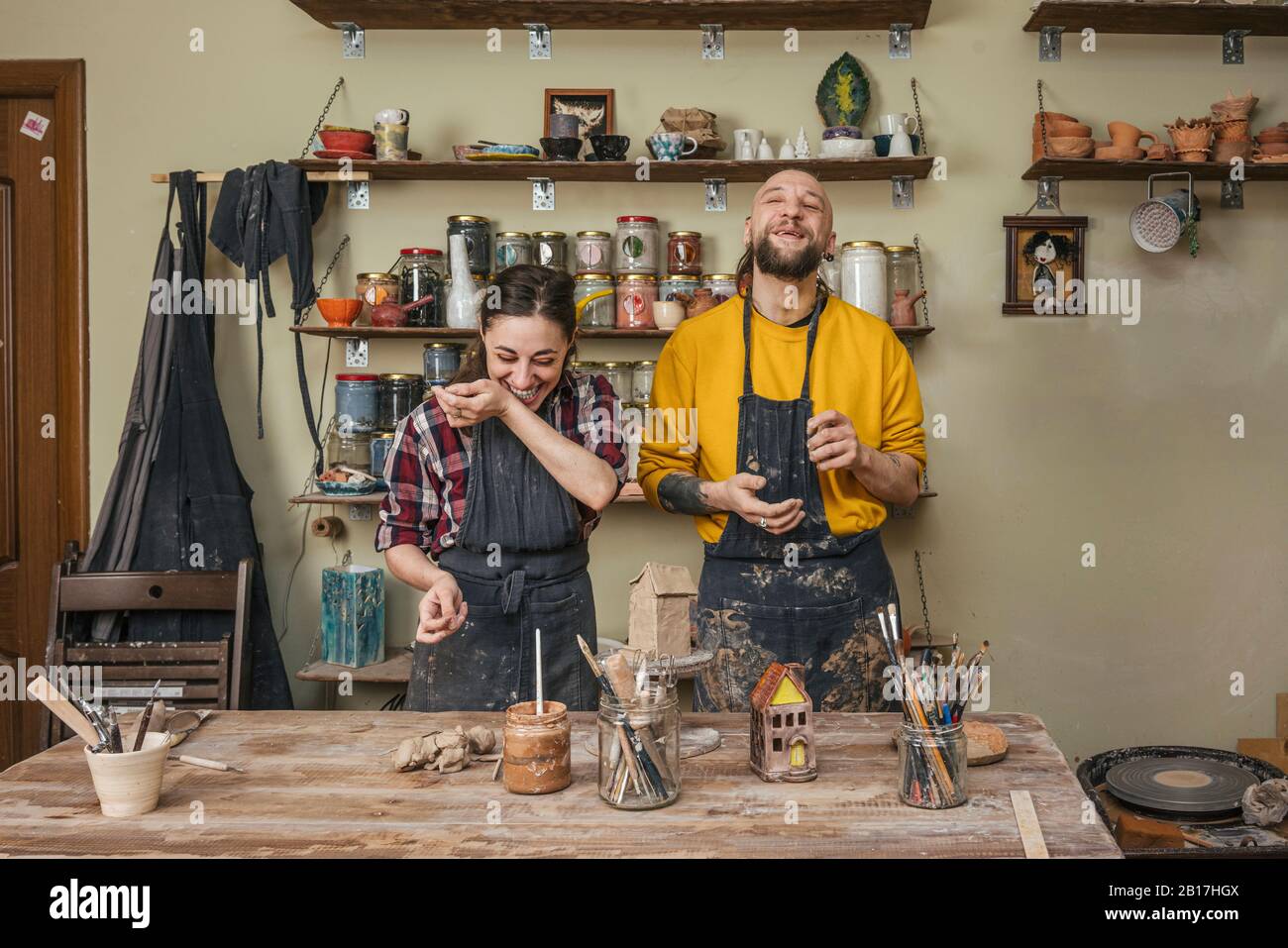Two laughing potters working together in workshop Stock Photo - Alamy