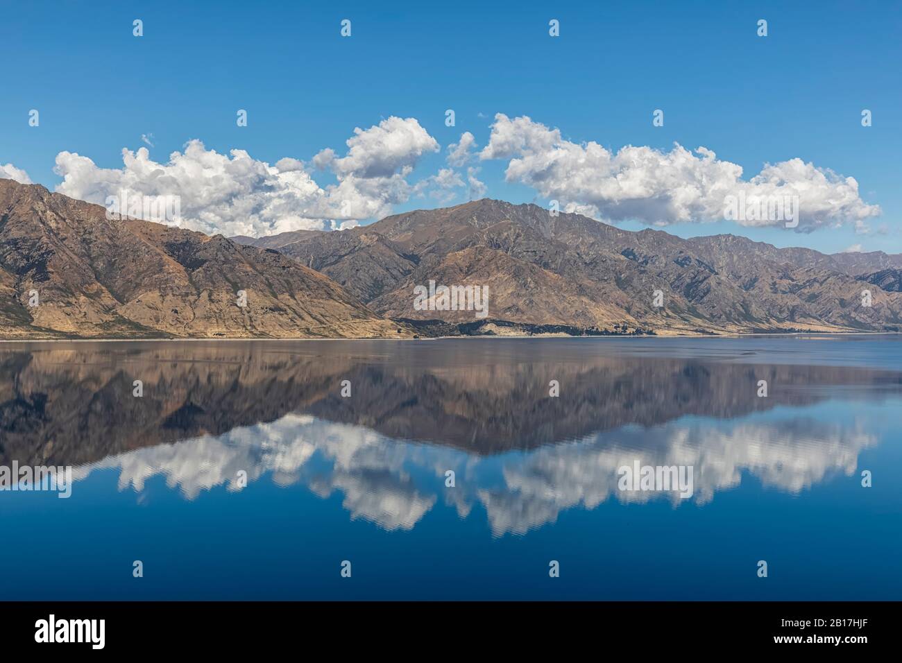 New Zealand, Queenstown-Lakes District, Wanaka, Hills and blue summer sky reflecting in Lake Hawea Stock Photo