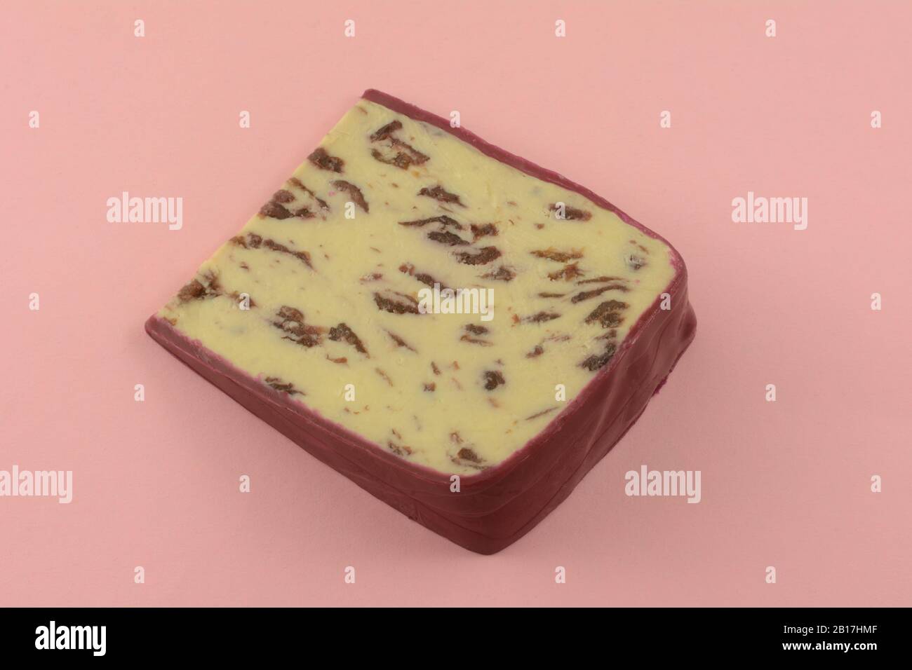 Slice of Wensleydale cranberry cheese with wax edges on pink background Stock Photo
