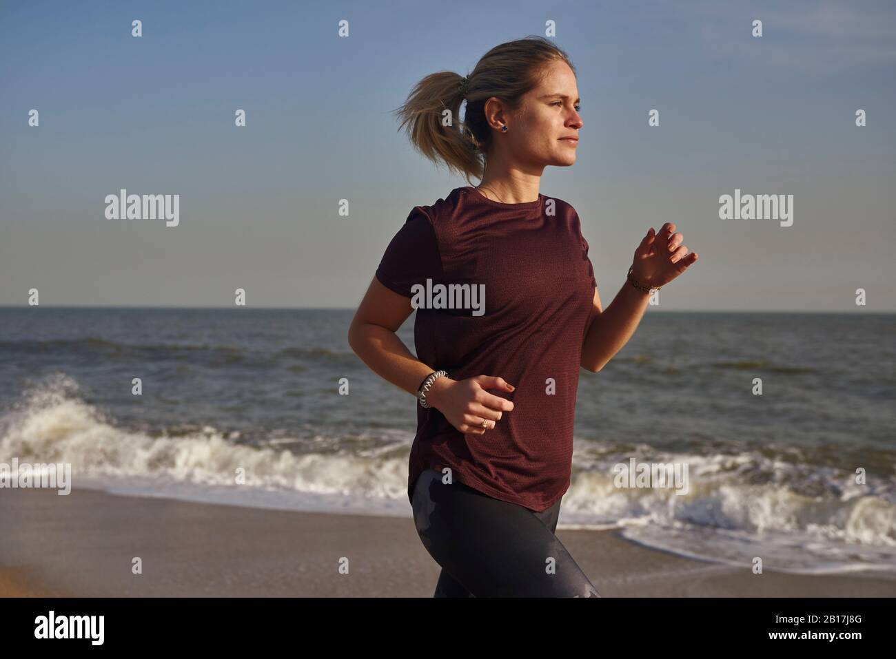 Young woman running on the beach Stock Photo