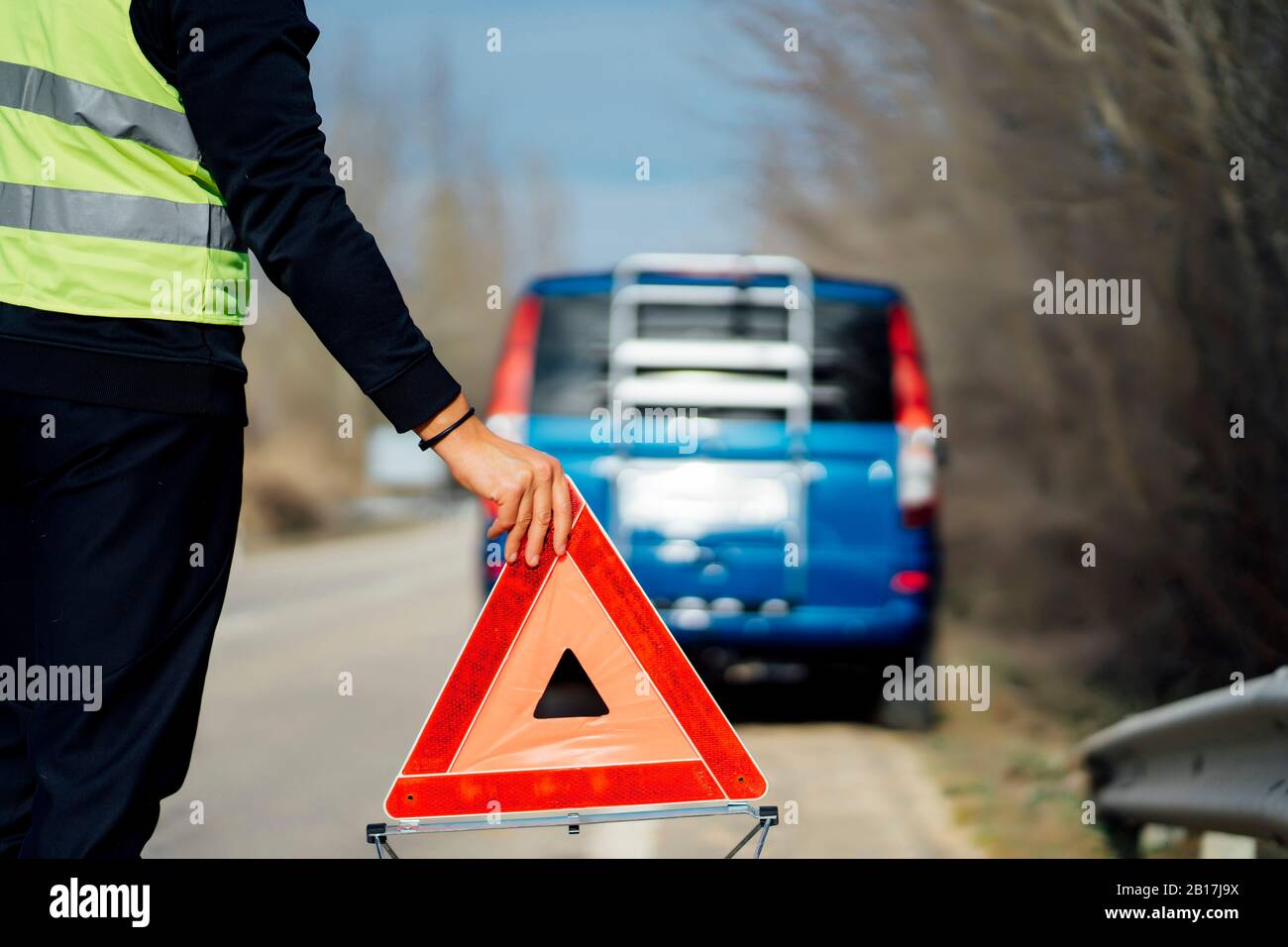 Man putting warning triangle on country road by van breakdown Stock Photo