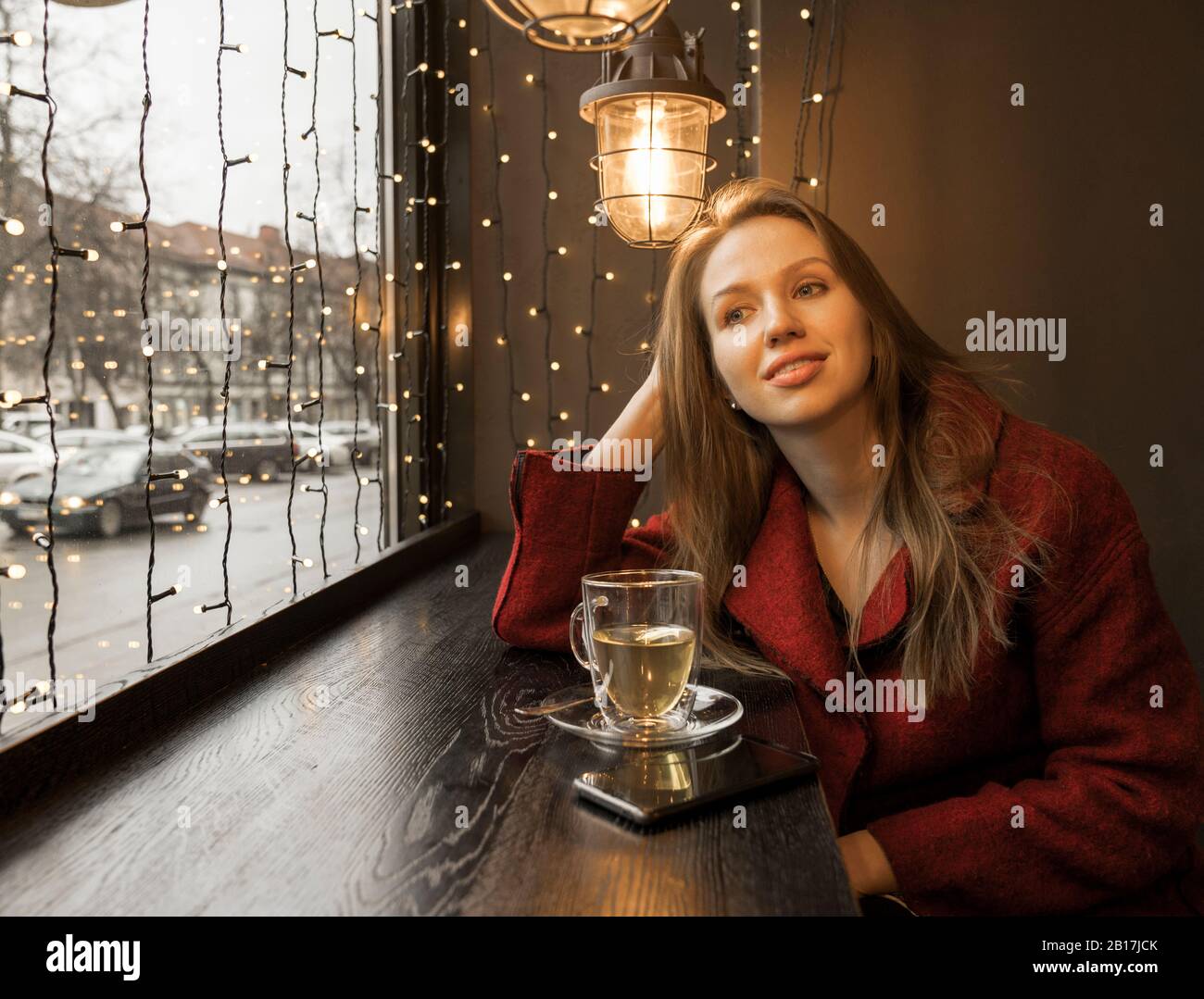 Portrait of relaxed young woman in a coffee shop looking out of window Stock Photo