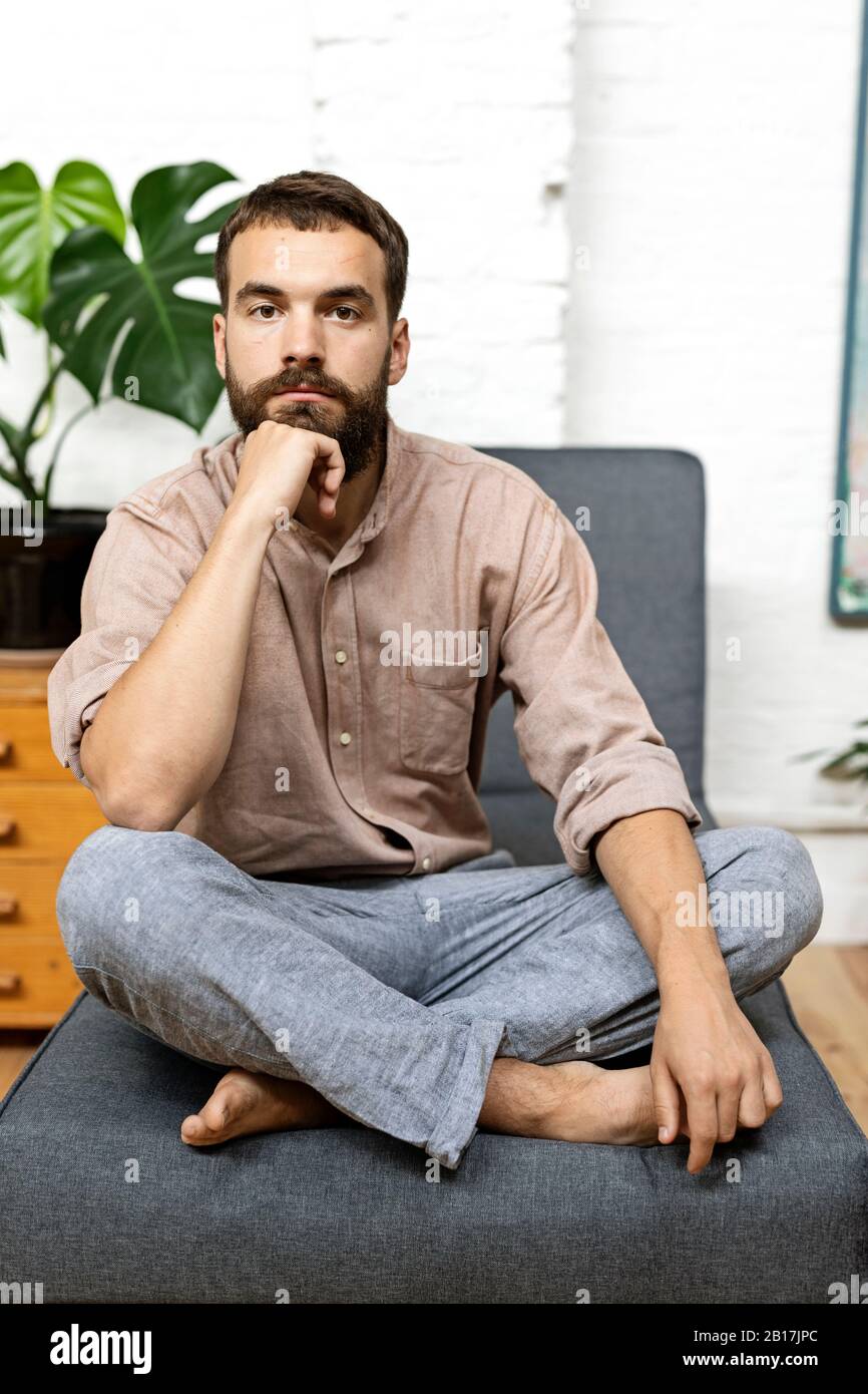 Young man sitting crosslegged on couch at home Stock Photo Alamy