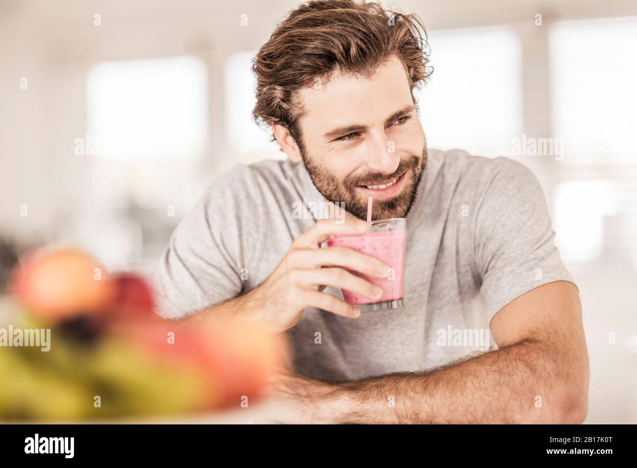 Young man smiling and drinking a fruit smoothie Stock Photo
