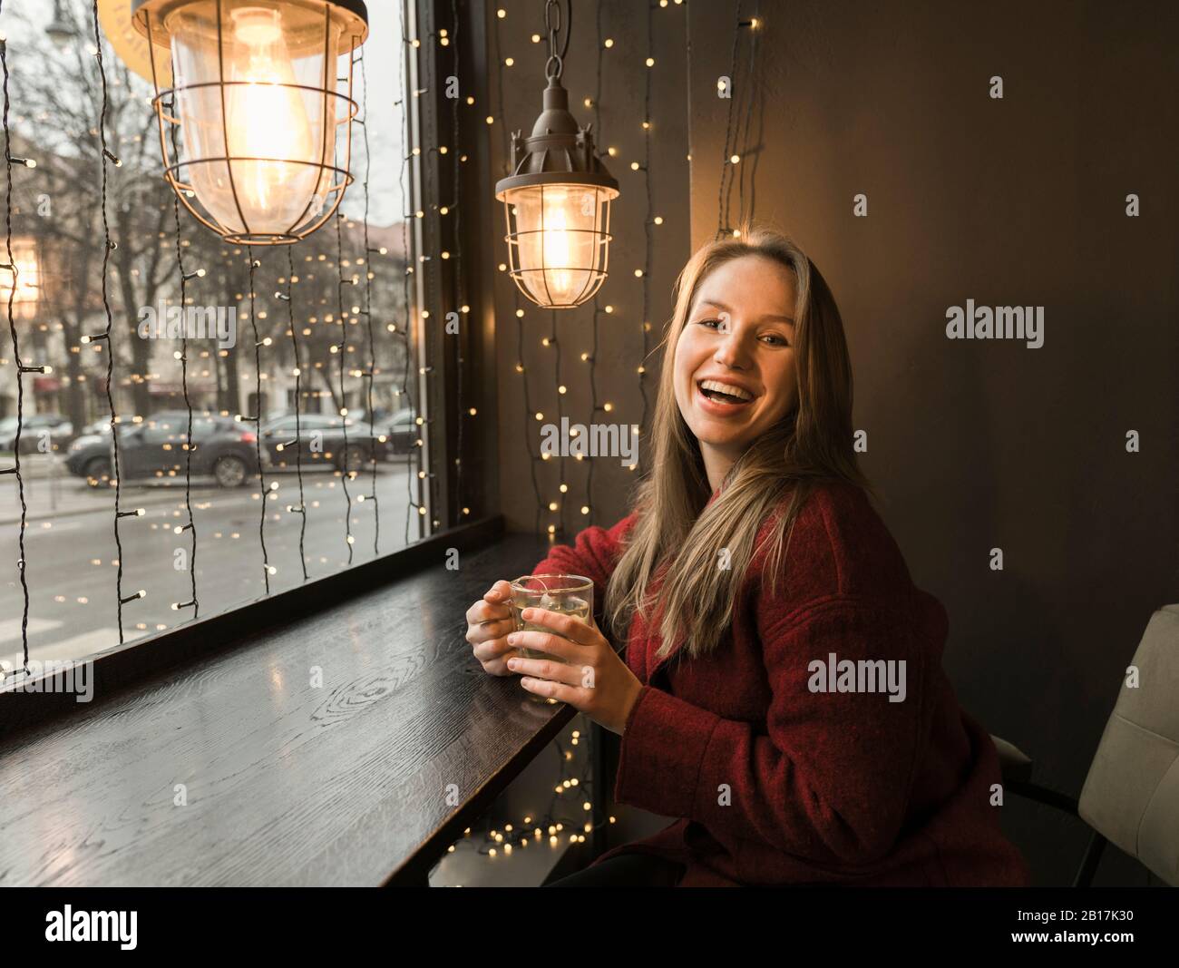 Portrait of laughing young woman with cup of tea in a coffee shop Stock Photo