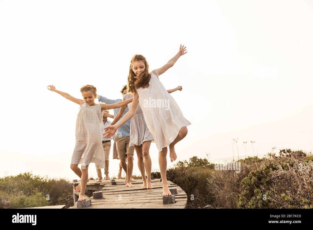 Large family enjoying the sunset balancing on a boardwalk Stock Photo