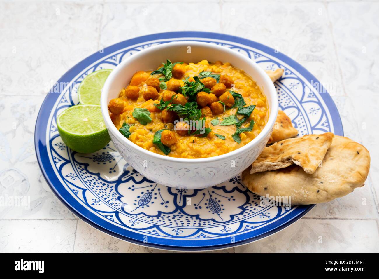 Vegan lentil curry with red lentils, sweet potatoes, spinach, roasted turmeric, chickpeas, with lime juice and coriander and naan bread Stock Photo