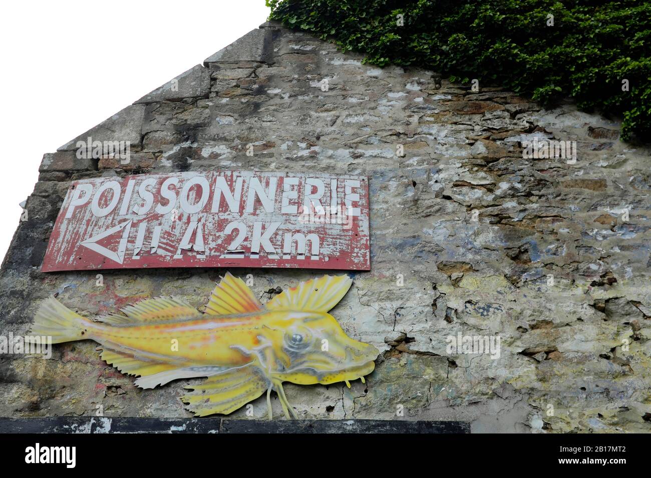 France, Brittany, Audierne, Hand painted fish shop sign with fish on old house wall Stock Photo
