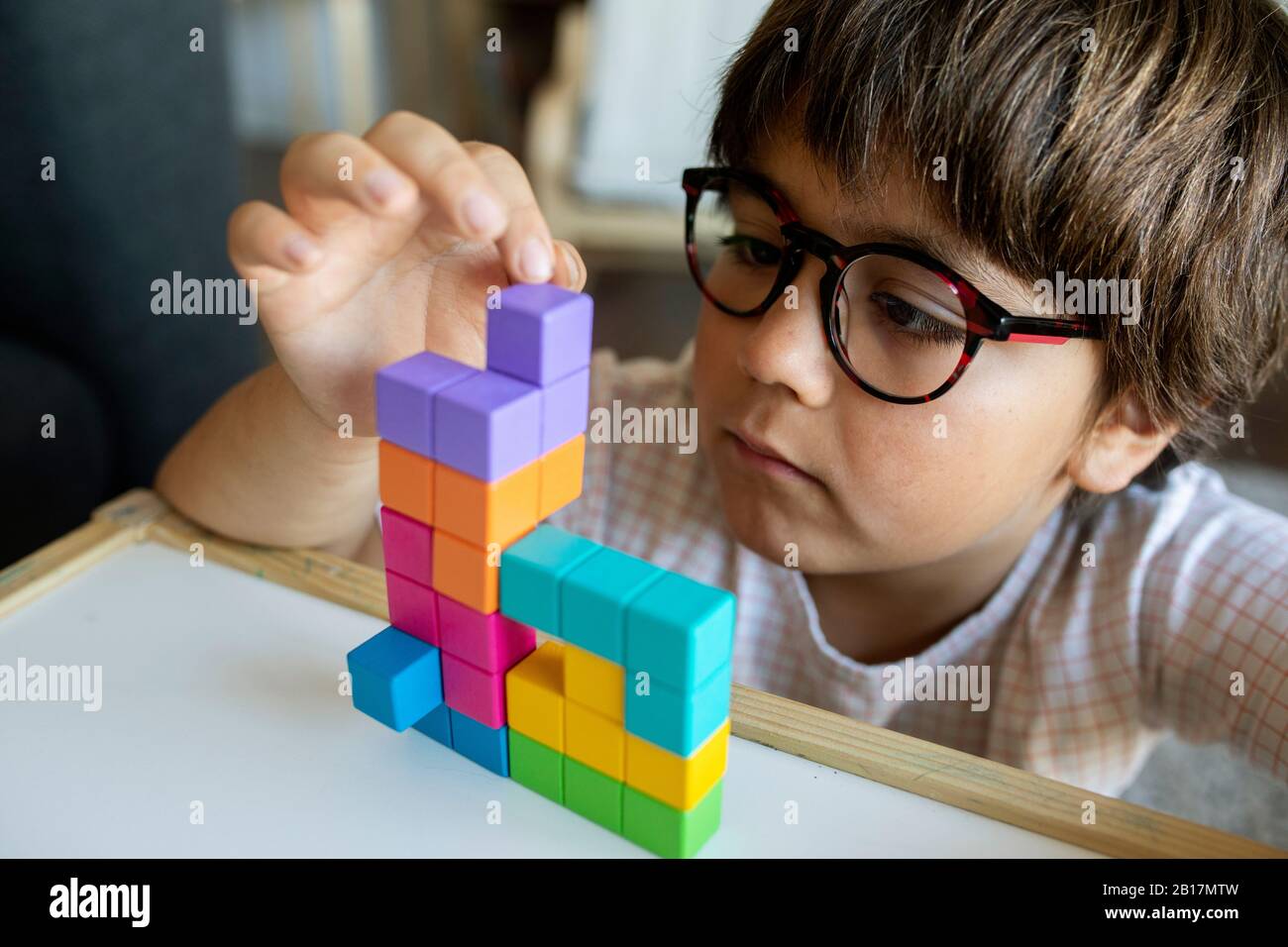 Portrait of little boy with glasses playing with building blocks Stock Photo