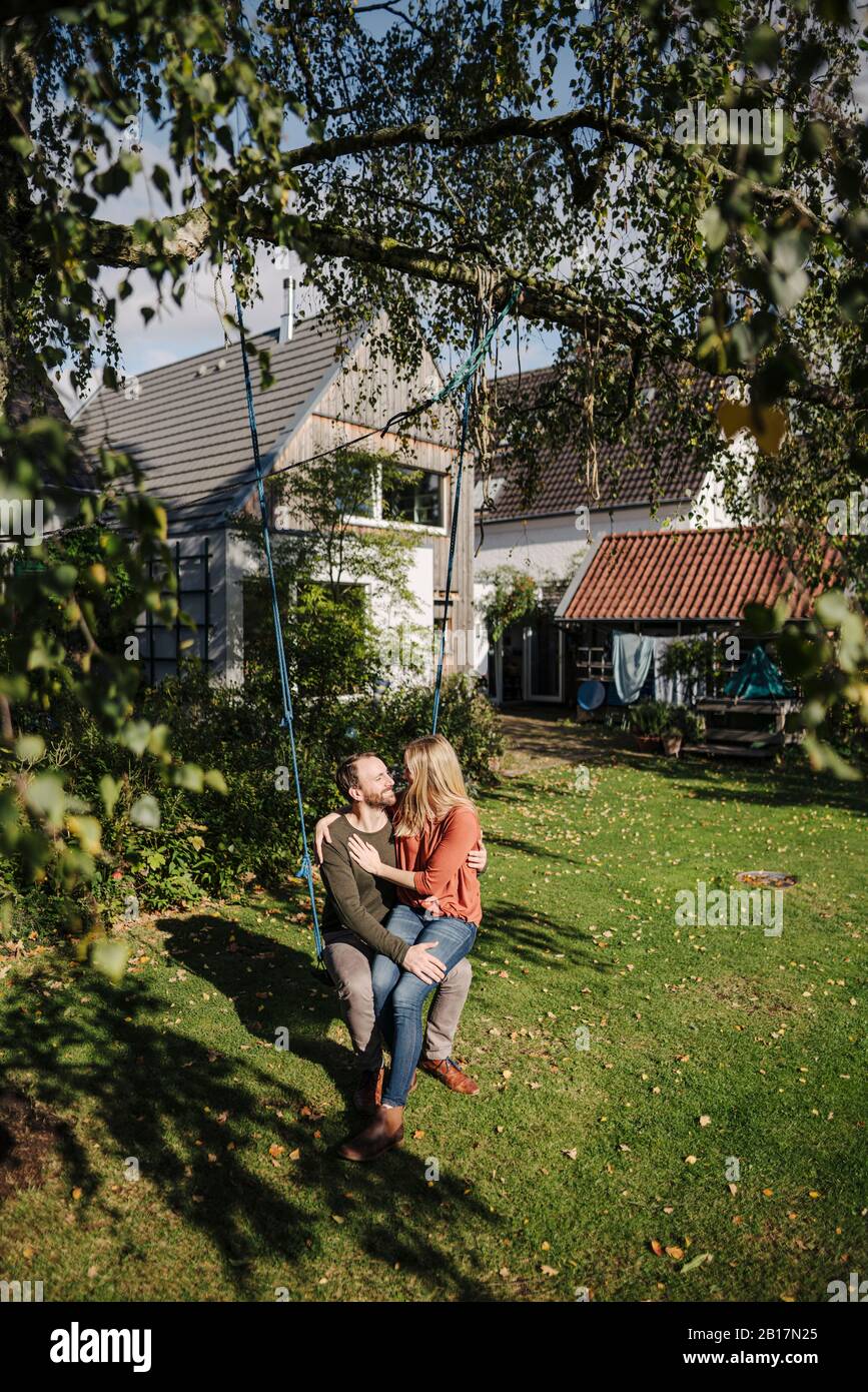 Affectionate couple sitting on swing in in their garden Stock Photo