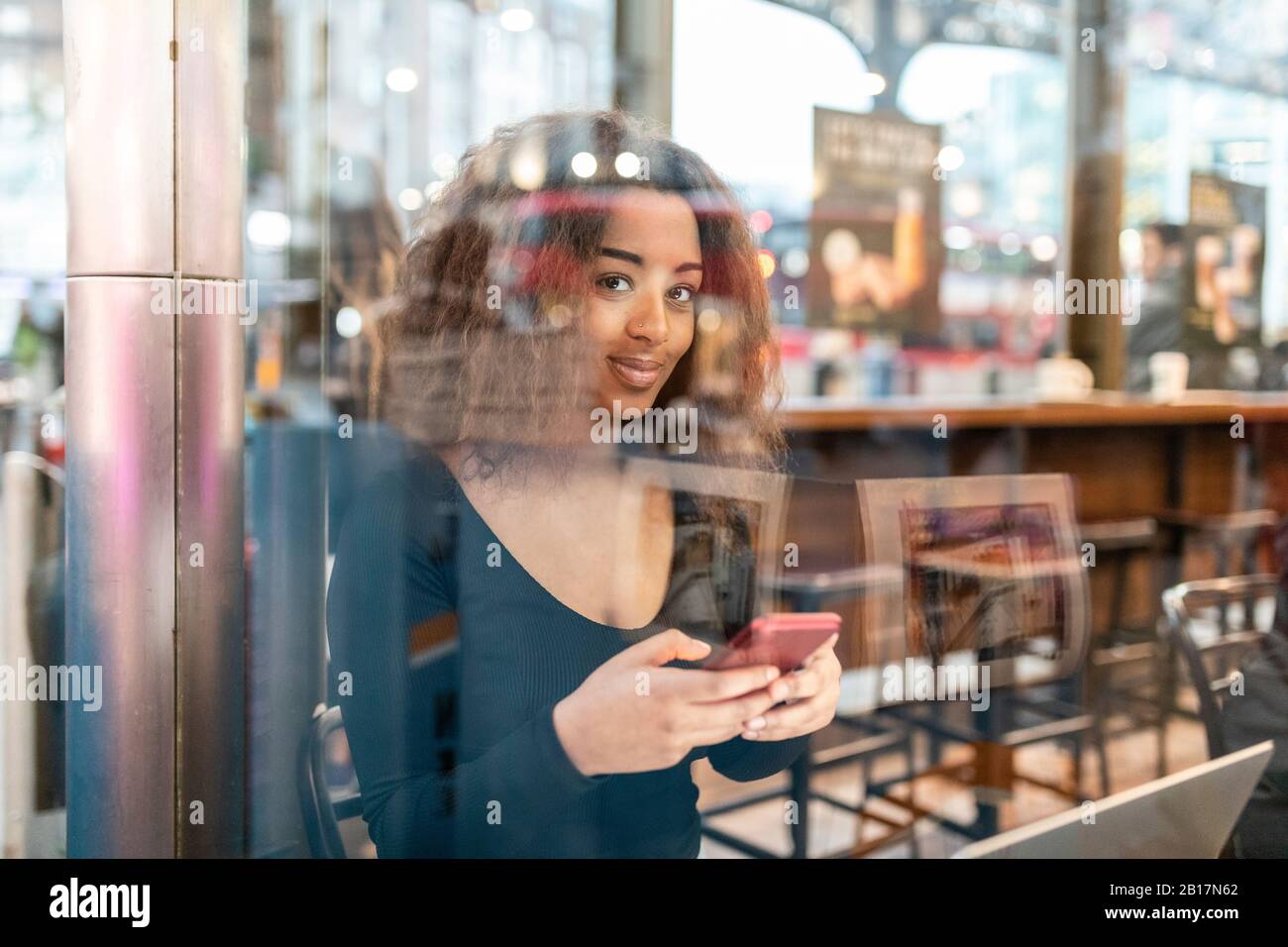 Portrait of smiling young woman using smartphone in a cafe Stock Photo