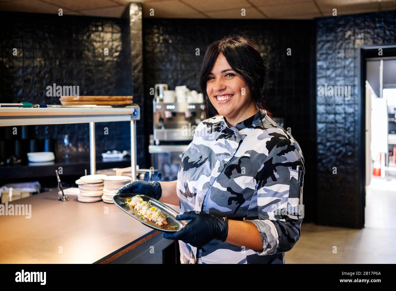 Portrait of smiling chef presenting a dish in restaurant kitchen Stock Photo