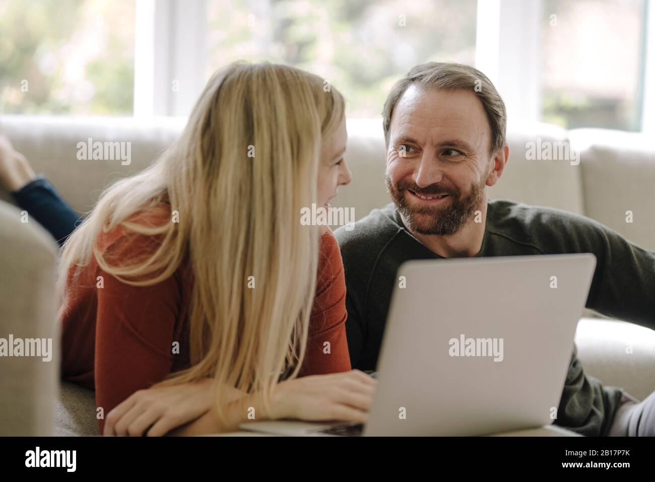 Couple sitting at home on couch, using laptop Stock Photo