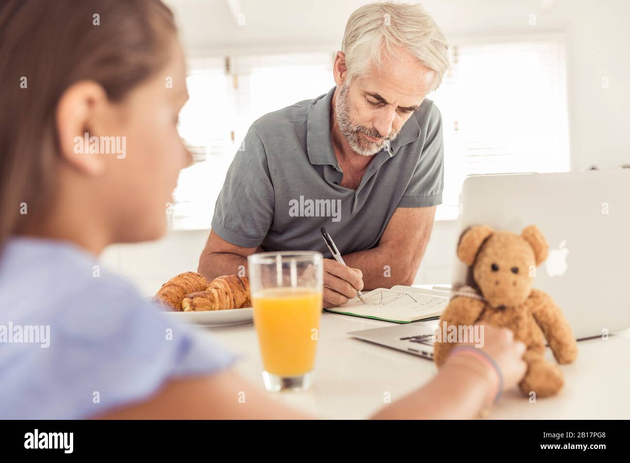 Mature man with daughter working in kitchen at home Stock Photo