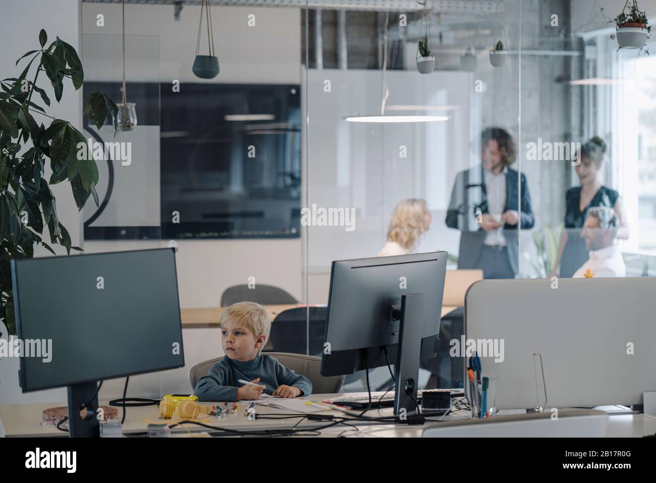 Boy painting in office with business team having a meeting Stock Photo