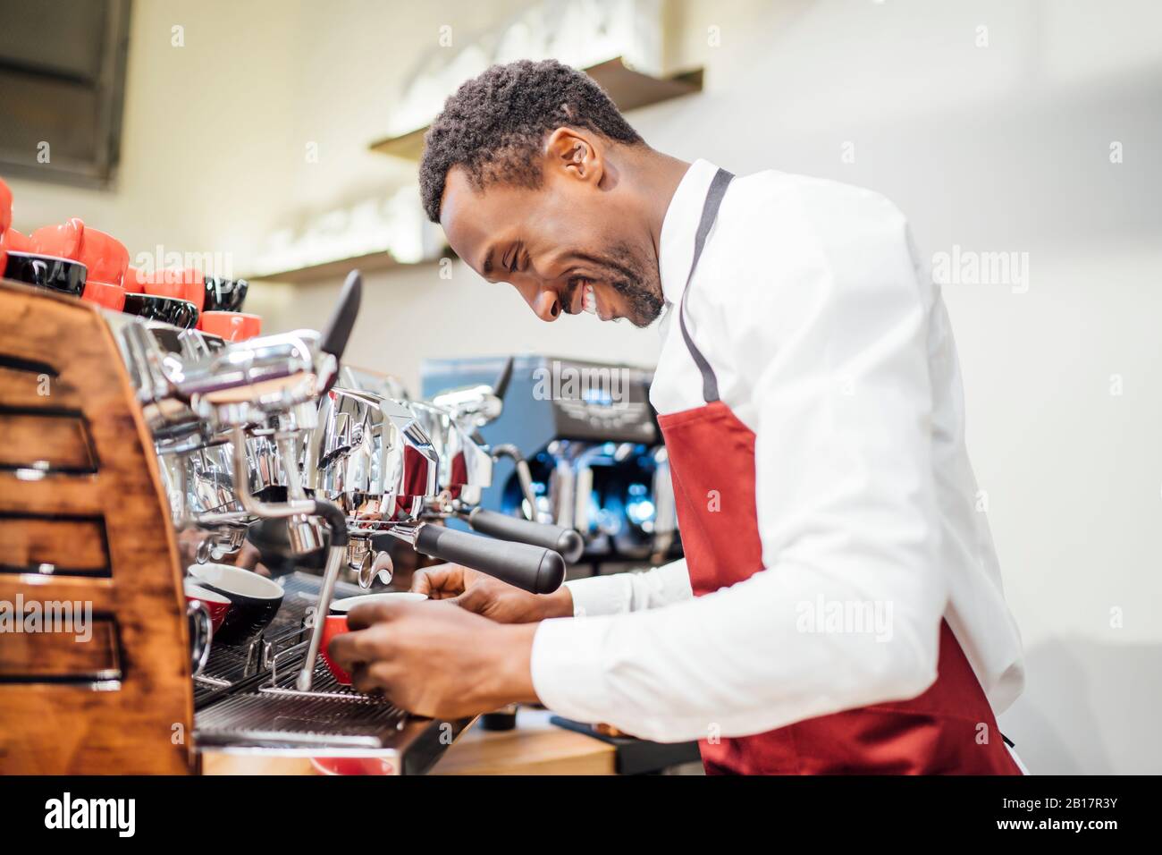 Smiling barista preparing a coffee in a coffee shop Stock Photo