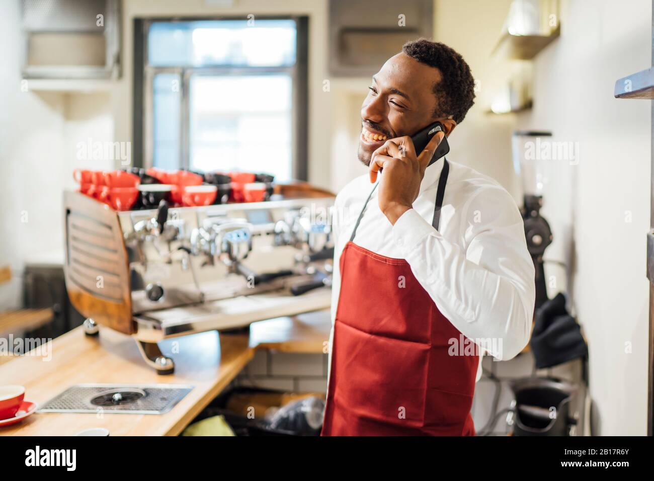 Happy barista on the phone in a coffee shop Stock Photo