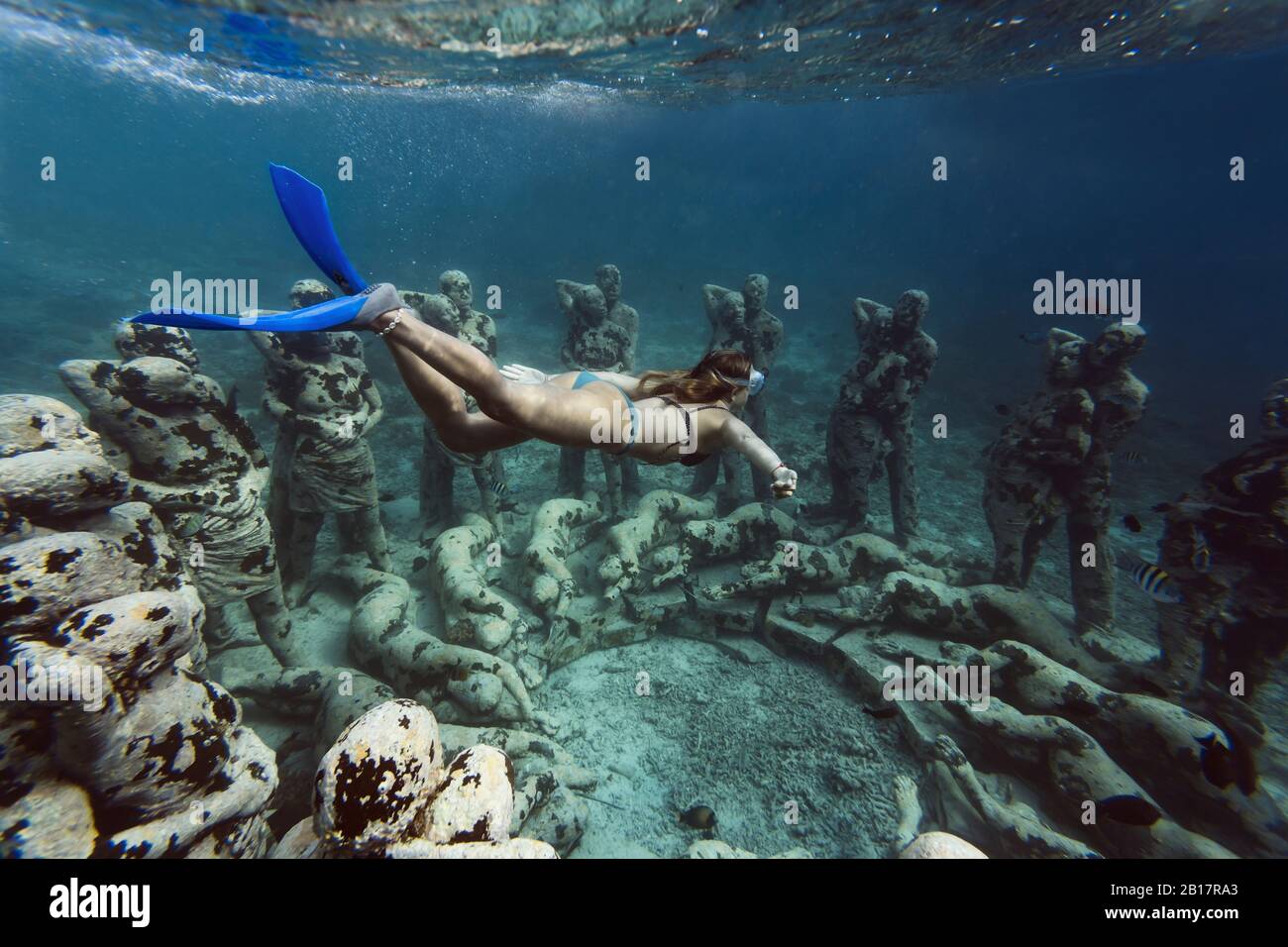 Woman swimming near underwater sculpture made by Jason deCaires Taylor