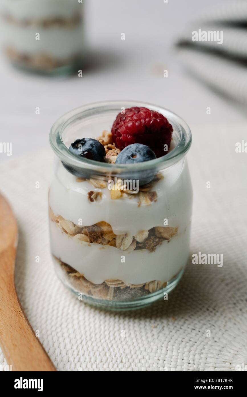 Small jar of granola with yogurt, blueberries and raspberry Stock Photo