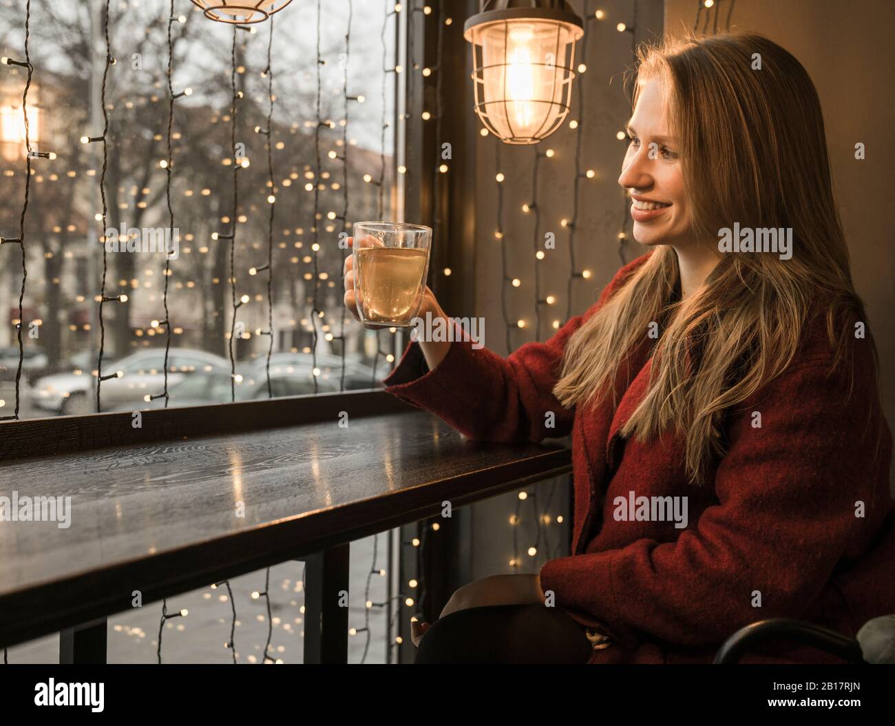 Smiling young woman with cup of tea in a coffee shop Stock Photo