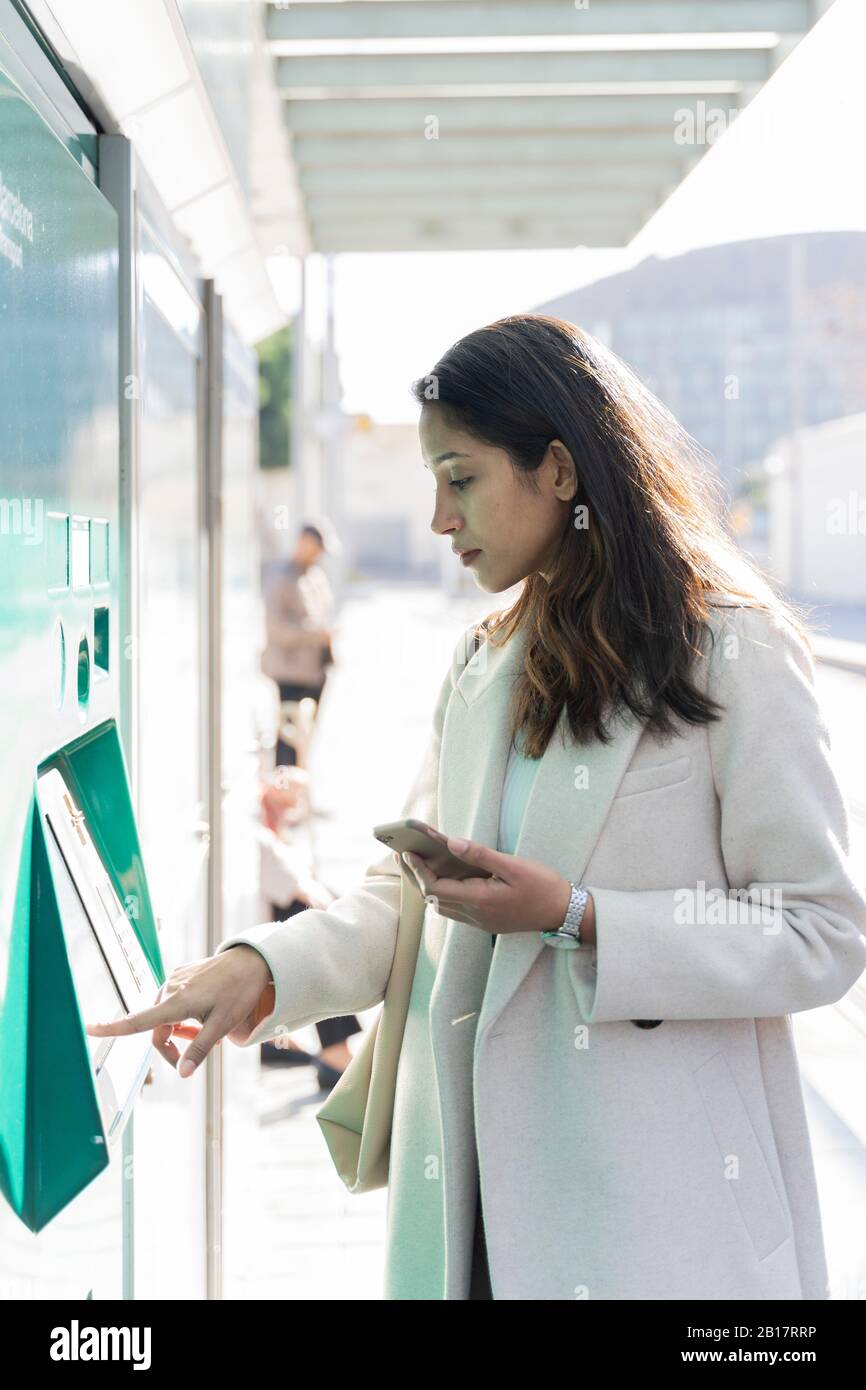 Young woman using ticket machine at tram stop Stock Photo - Alamy