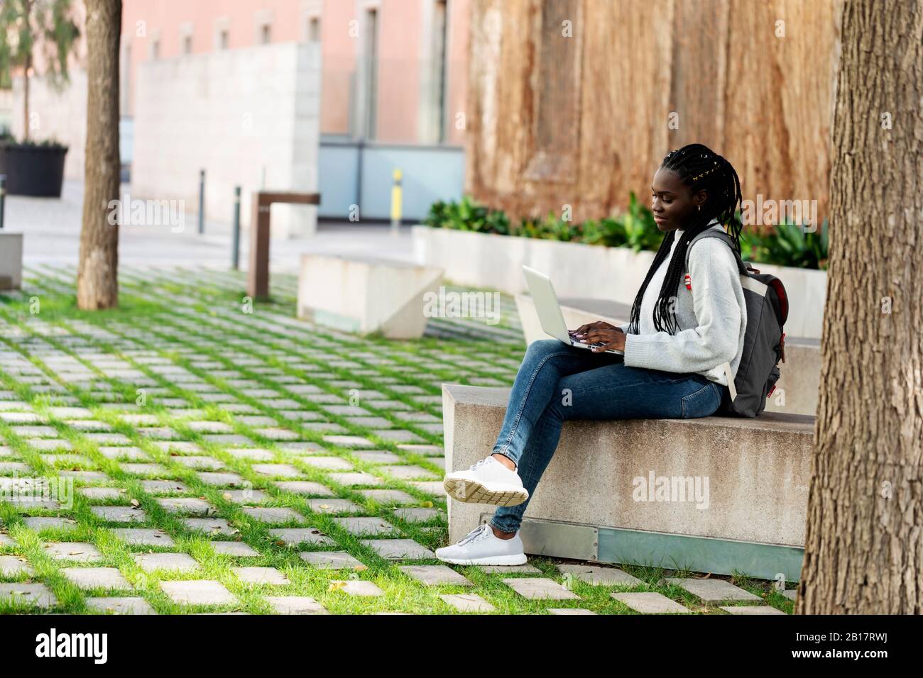 Female student using laptop on a bench Stock Photo