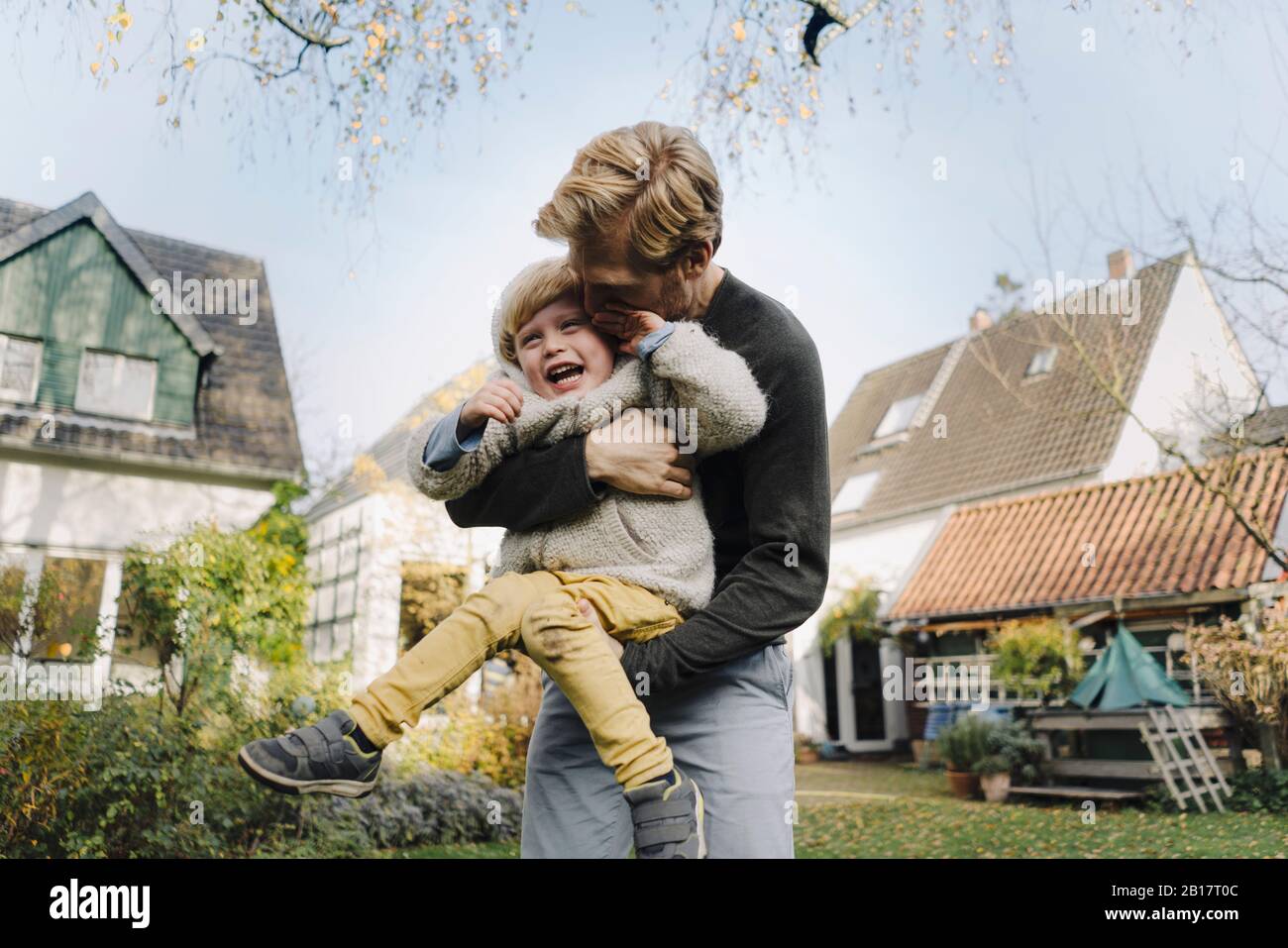 Happy father playing with son in garden Stock Photo
