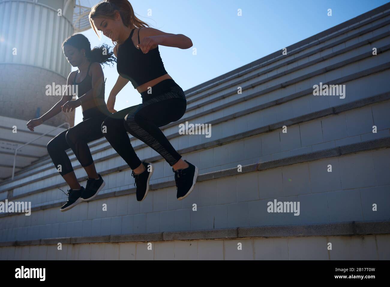Sportswomen jumping from a stair Stock Photo