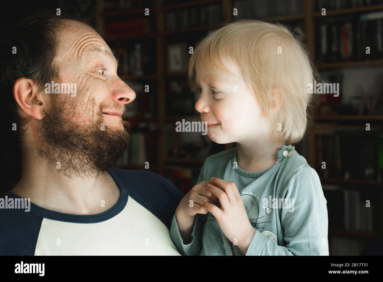 Father grimacing at little daughter at home Stock Photo