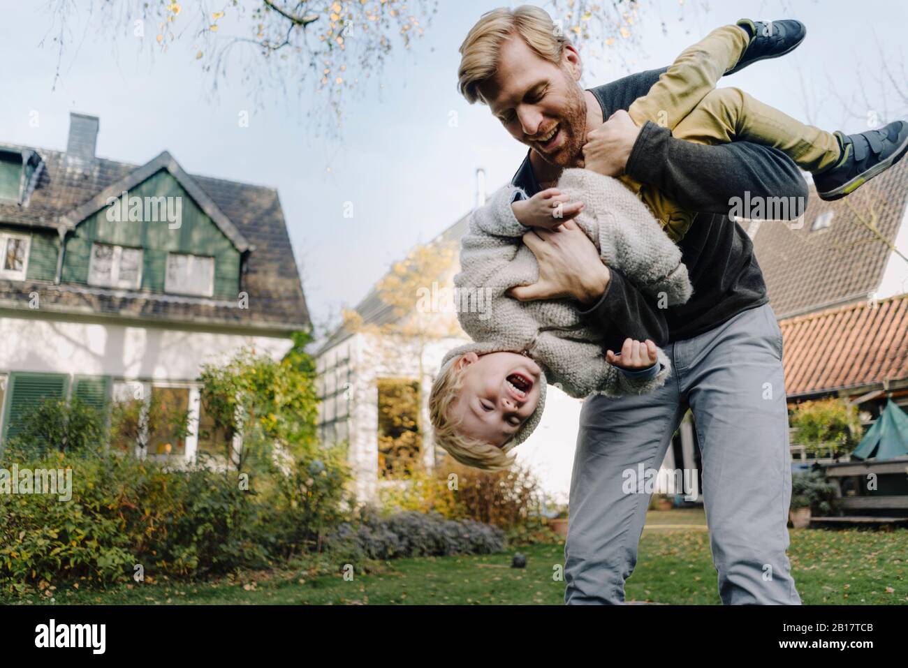 Happy father playing with son in garden Stock Photo