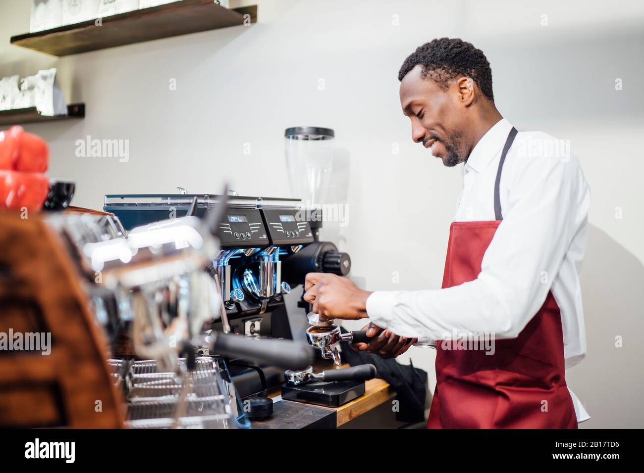 Smiling barista preparing a coffee in a coffee shop Stock Photo
