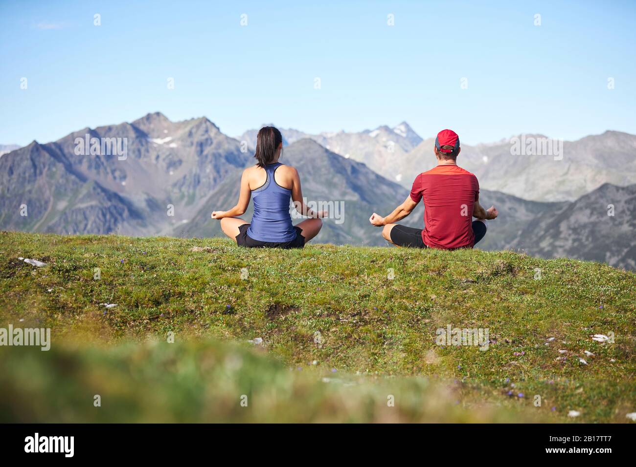 Man and woman meditating in the mountains, rear view Stock Photo