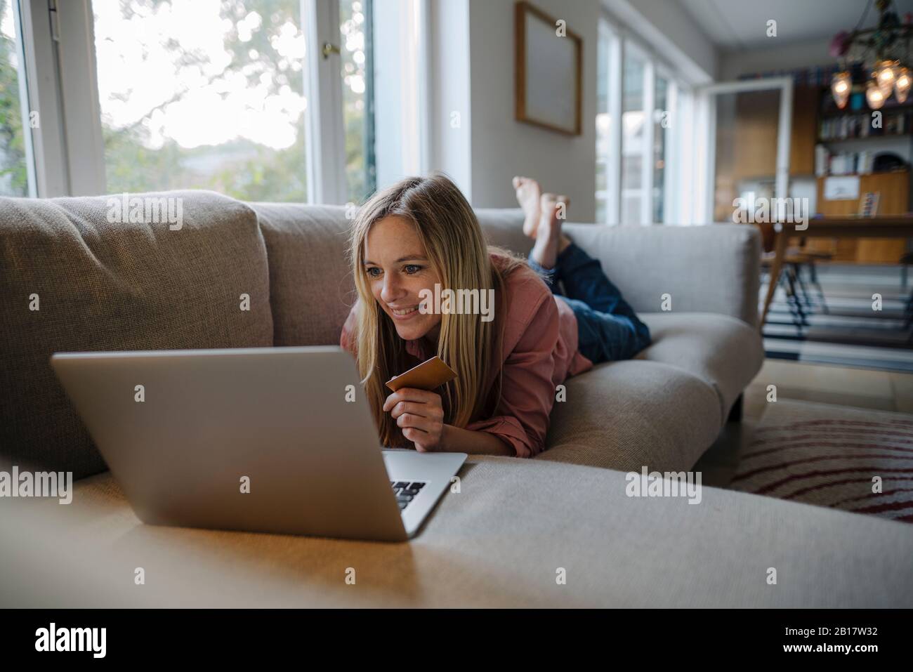 Woman lying on couch, using laptop Stock Photo - Alamy