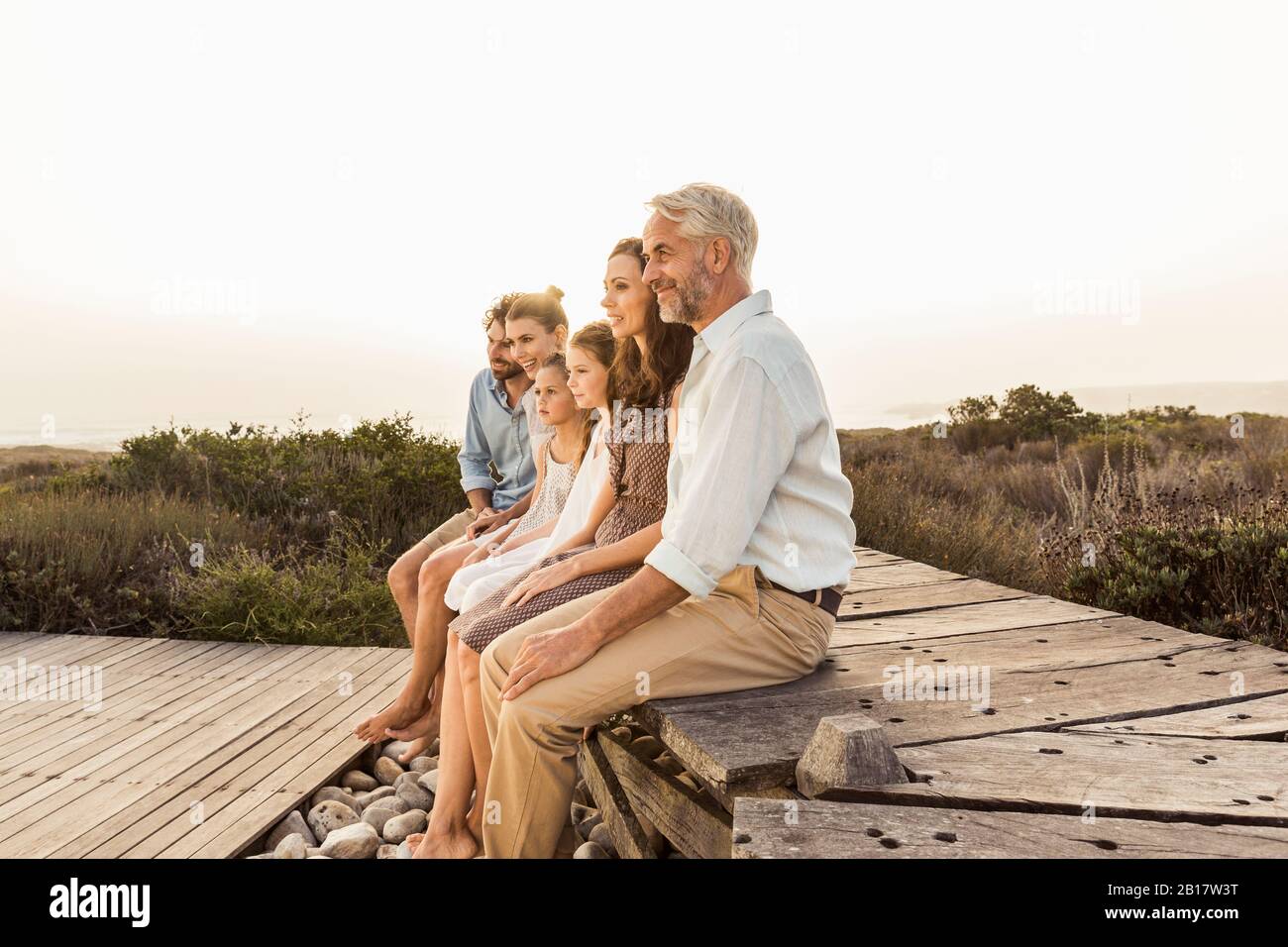 Large family enjoying the sunset sitting on a boardwalk Stock Photo