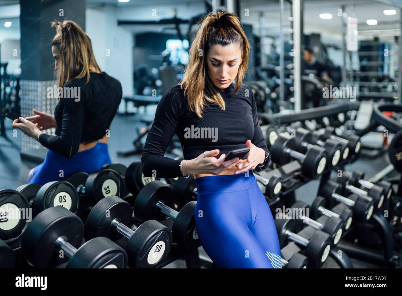 Woman having a break in gym using smartphone Stock Photo