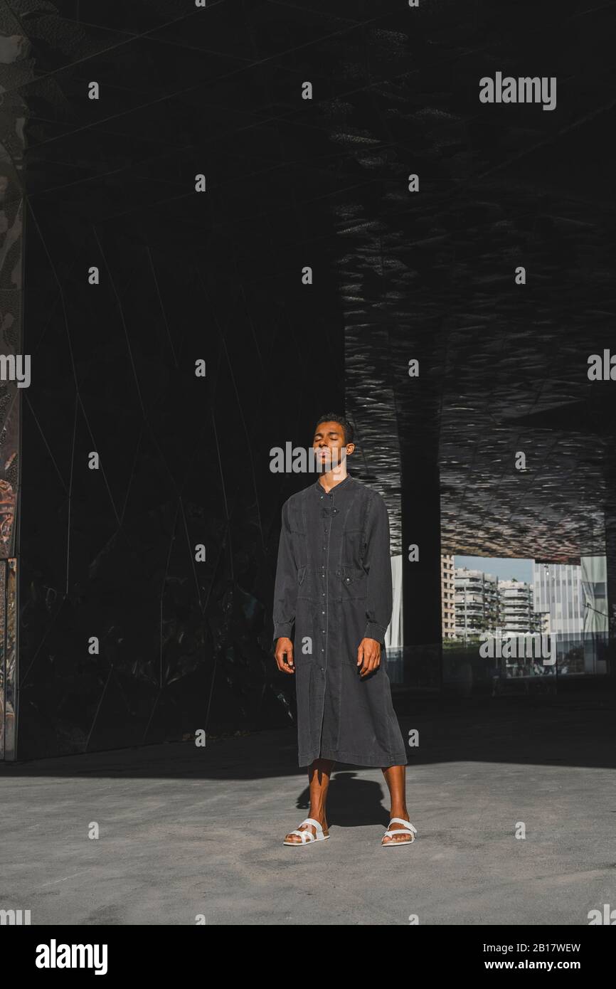 Young man wearing black kaftan standing outdoors Stock Photo